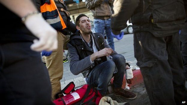 An injured man sits as he is treated by paramedics at the scene of a stabbing in Tel Aviv, Israel, 21 January 2015