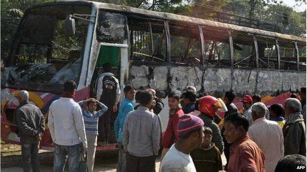 Onlookers surround the wreckage of a burnt bus allegedly set on fire by Bangladesh Nationalist Party (BNP) supporters during a blockade in Rangpur on January 14