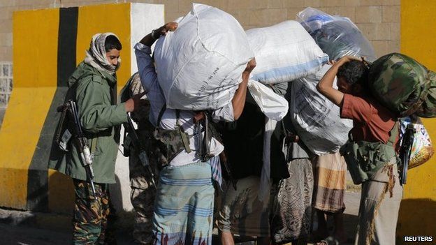 A Houthi fighter screens members of the Yemeni presidential guards - wearing civilian clothes - as they leave the presidential palace with their belongings in Sanaa (21 January 2015)