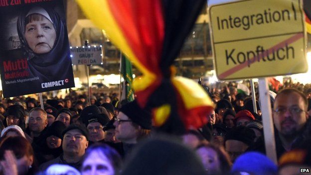 Participants of a Legida demonstration, a local offshoot of the Pegida in Leipzig, carry a placard depicting German Chancellor Angela Merkel wearing a headscarf