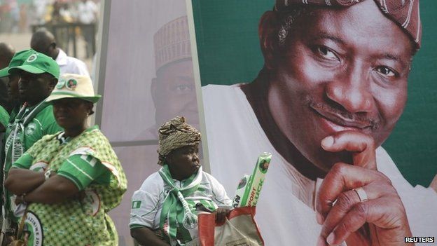 A woman sits beside an electoral poster of Nigeria's President Goodluck Jonathan during the flag-off for his campaign for a second term in office, in Lagos on 8 January 2015