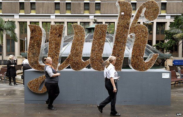 Two smokers walk past a giant sign saying 'yuk', made from cigarette butts in an effort to get smokers to bin their butts in the Sydney central business district on 25 September 2014.