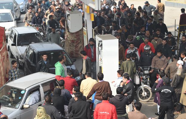 Pakistani motorcyclists queue at a petrol station in Lahore on January 20