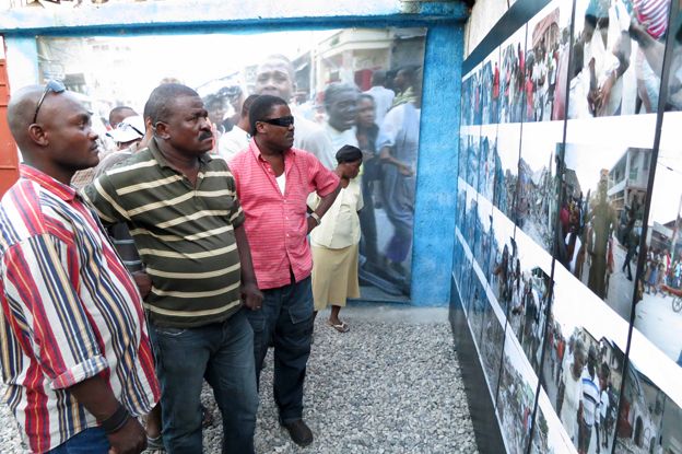 People looking at Morel's photos in Haiti