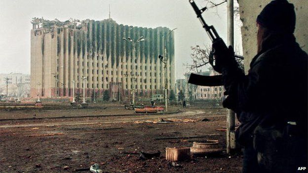 Picture taken on January 10, 1995 shows a Chechen fighter taking cover from sniper fire in a building across the square from the presidential palace destroyed by Russian artillery bombardments.