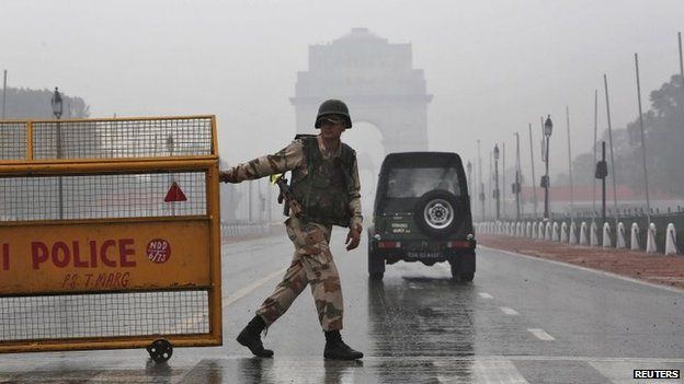 An Indian security personnel pulls a barricade to block the road in front of India Gate as it rains in New Delhi January 22, 2015.