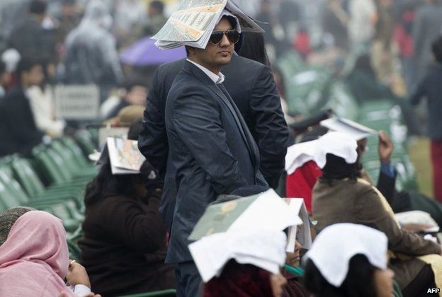 An Indian spectator tries to protect himself from the rain as he attends the Republic Day Parade