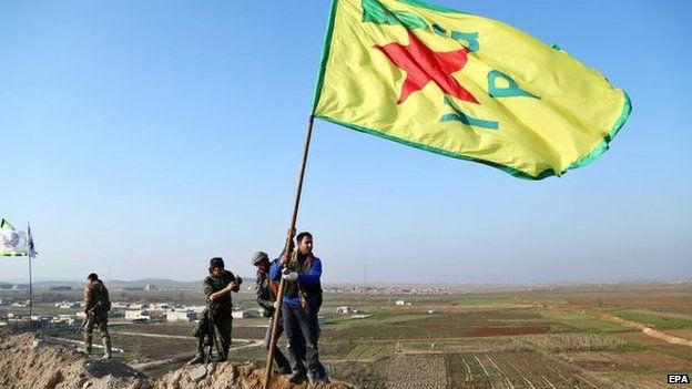 Kurdish Popular Protection Units (YPG) raise its flag on a hill overlooking Kobane (26 January 2015)