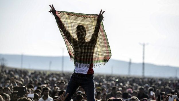 Kurdish people flash the V for victory sign during a celebration rally near the Turkish-Syrian border at Suruc, in Turkey's Sanliurfa province, on Tuesday