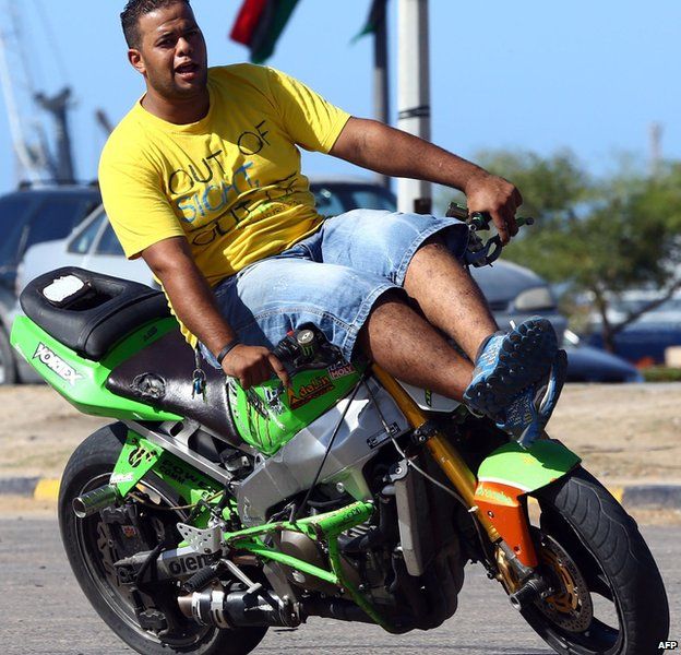 A Libyan man shows off his skill while free riding on a motorbike in Tripoli on 30 October 2014