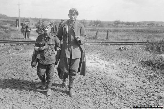 Battle of Epehy. Wounded and Prisoners coming in, near Epehy, 18th September 1918. The wounded soldier in the foreground is from a Bantam unit.