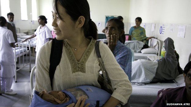 Jane Chen holding a baby wearing an Embrace baby warmer at a hospital in India