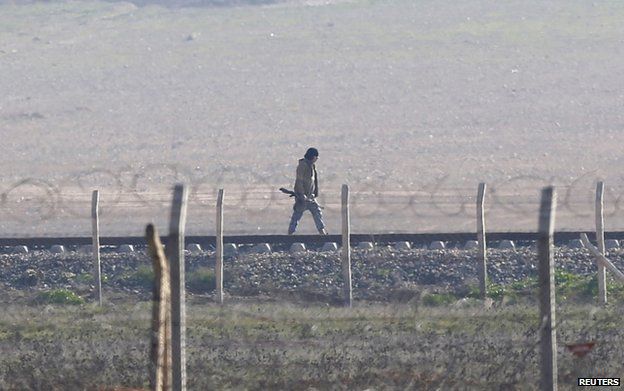 A presumed IS fighter patrols the Syrian side of the border with Turkey near Tal Abyad, Syria, 29 January