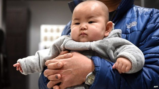 This picture taken on 19 January 2015 shows a Chinese baby in the arms of his father at a furniture store in Beijing