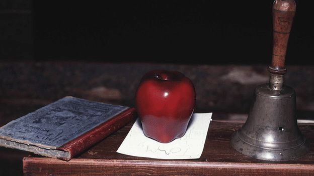 A book, apple and bell on a desk