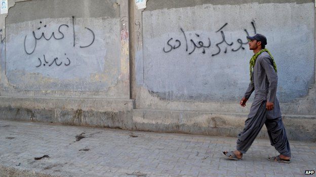 A Pakistani man walks past a wall graffiti reading 'Abu Bakr al-Baghdadi', leader of the Islamic State (IS) jihadist group in Iraq, in Quetta on November 24, 2014