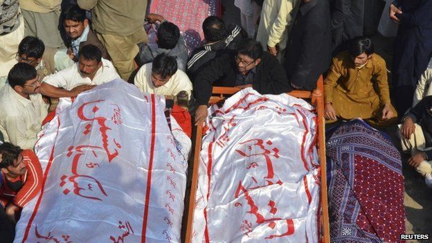 Relatives sit near the bodies of victims who were killed in Friday's explosion at a Shia mosque in Shikarpur (31 January 2015)
