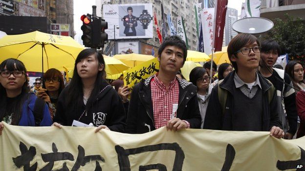 Student leader Alex Chow (centre) carries a banner with other students during the democracy march (01 February 2015)
