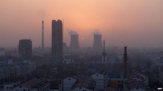 A photo taken on 9 March 2013 shows the sun setting behind chimneys rising above the skyline of Baoding, Hebei province, some 140 km south of Beijing.