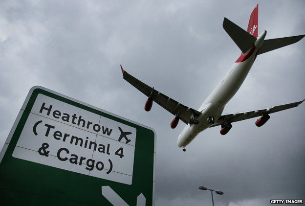 Plane comes in to land over road sign for Heathrow airport