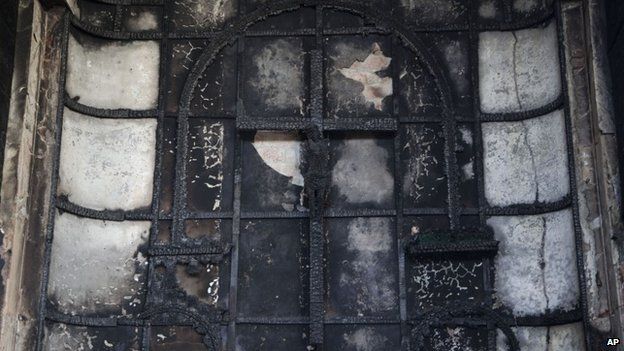 A burnt crucifix stands at the altar of St. Sebastian"s Church after a fire destroyed the church on Monday, in New Delhi, India, Tuesday, Dec. 2, 2014.