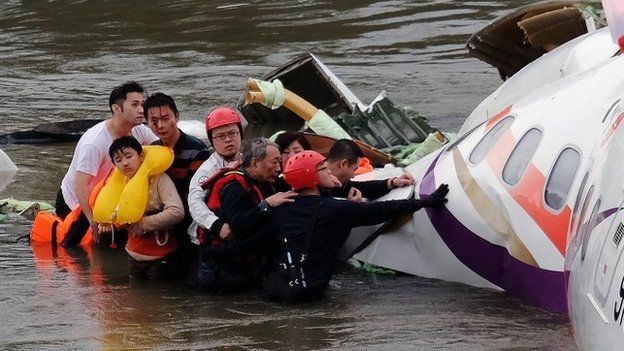 Rescue workers pull survivors from the sunken wreckage of TransAsia flight GE235
