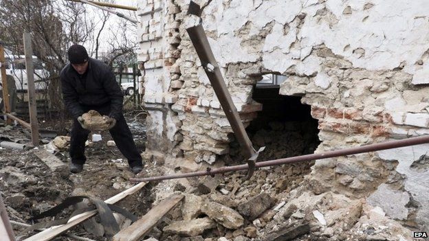 A man inspects his damaged home after shelling in Sartana village of Mariupol area, Ukraine