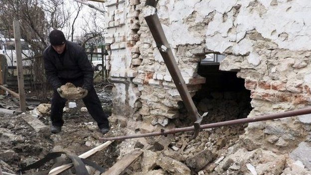 A man inspects his damaged home after shelling in Sartana village of Mariupol area, Ukraine