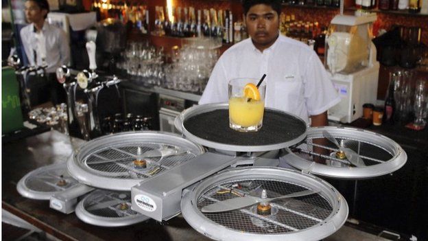 A bartender watches as an Infinium-Serve Flying Robot takes off with an order at a restaurant during a pilot demonstration for the media in Singapore 5 February 2015