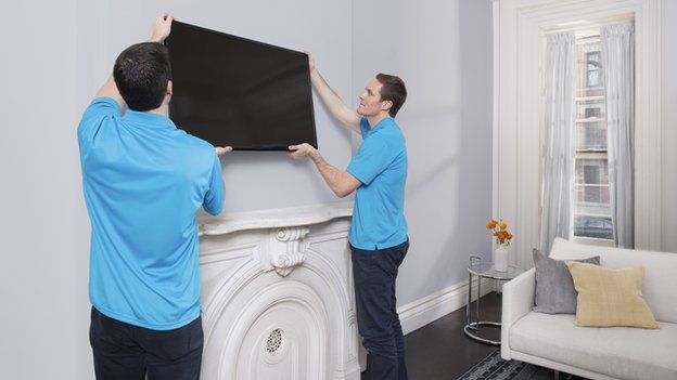 Handy tradesmen fitting a television