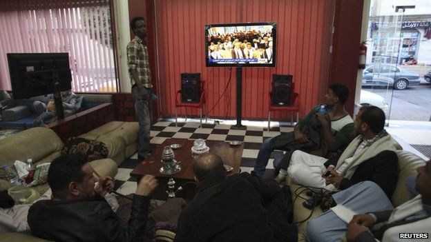 People watch television as an announcement by the Houthi movement on dissolving the parliament is made in Sanaa