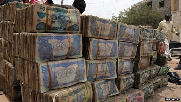 Somali money changer talks on phone on March 8, 2012 next to piles of banknotes