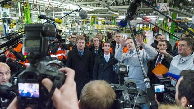 Members of the media surround French Prime Minister Manuel Valls (C) and Socialist Party (PS) parliamentary candidate Frederic Barbier (C-L) as they visit the French carmaker PSA Peugeot plant in Montbelliard, eastern France, on February 5, 2015