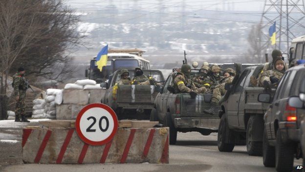 Ukrainian government troops sit in the back of pick-up trucks as they pass a checkpoint near the town of Mariupol, Ukraine, Tuesday 10 February 2015