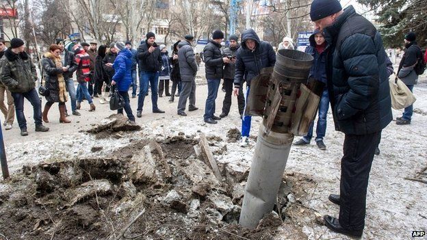 People look at a rocket stuck in the ground in Kramatorsk after shelling in eastern Ukrainian city - 10 February 2015