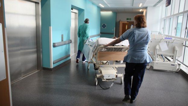A nurse and another member of hospital staff pushing a trolley bed in a hospital