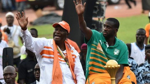 Ivorian President Alassane Ouattara and Ivory Coast captain Yaya Toure wave at the crowd