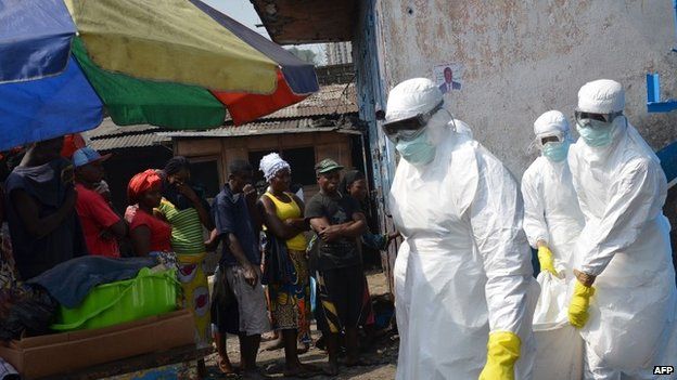 Red Cross workers, wearing protective suits, carry the body of a person who died from Ebola during a burial with relatives of the victims of the virus, in Monrovia, 5 January 2015