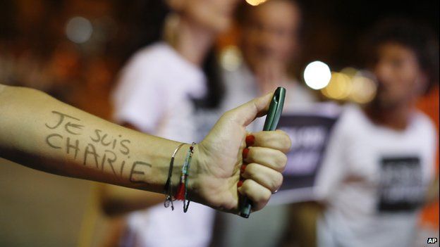 Outstretched arm holding pen, with "je suis charlie" written on arm