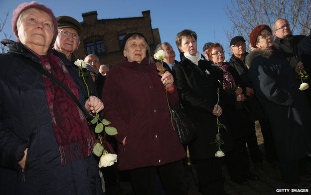 Visitors and survivors of the February 13, 1945 allied firebombing of Dresden, as well as Dresden Mayor Helma Orosz (fifth from right), arrive to lay white roses at the former train station where the Nazis shipped Dresden Jews to concentration camps