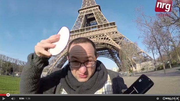 A man placing a kippah on his head beside the Eiffel Tower