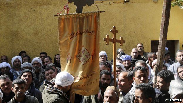 A Coptic man kisses a prayer banner before a mass at a church in the south of Cairo for the Egyptian Coptic men who were killed in Libya