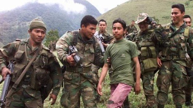 Soldiers escort a 13-year-old captured teenage rebel of the Farc in the mountains of Santander state on 21 December, 2000.