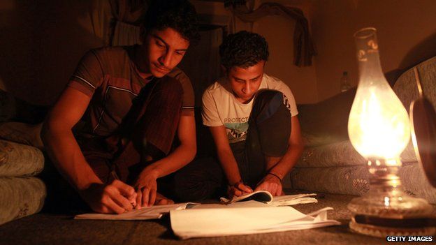 Two boys studying by the light of an oil lamp