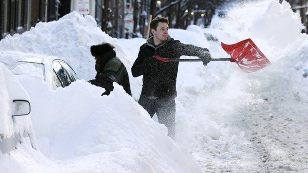 John Mensch shoves snow around a car buried in almost a four foot drift in Boston on 3 February 2015