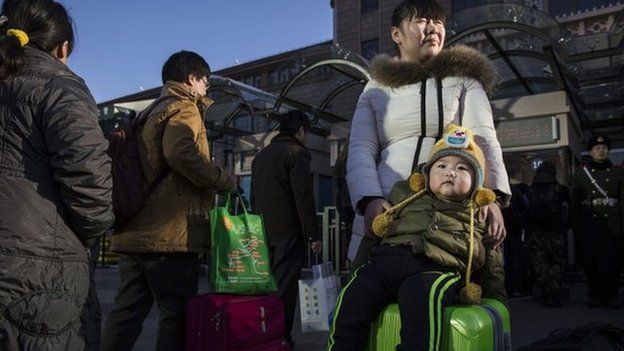 A Chinese woman and her son wait in line with others as they leave for the Spring Festival at a local railway station on 17 February 2015 in Beijing, China