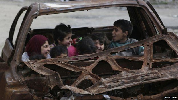 Children play inside the wreckage of a burnt vehicle at al-Myassar neighborhood in Aleppo (16 May 2015)