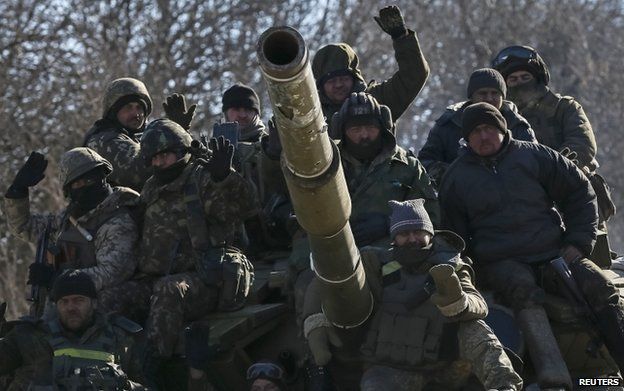 Ukrainian servicemen ride on a military vehicle as they leave area around Debaltseve, eastern Ukraine near Artemivsk, 18 February 2015