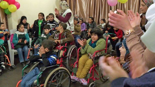 Children in wheelchairs clap along to the music