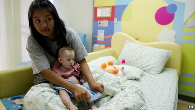 Thai surrogate mother Pattaramon Chanbua (L) holds her baby Gammy, born with Down's Syndrome, at the Samitivej hospital, Sriracha district in Chonburi province on August 4, 2014